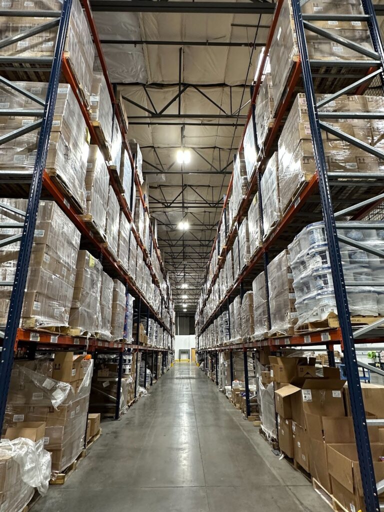 A warehouse aisle filled with large, plastic-wrapped cardboard boxes.