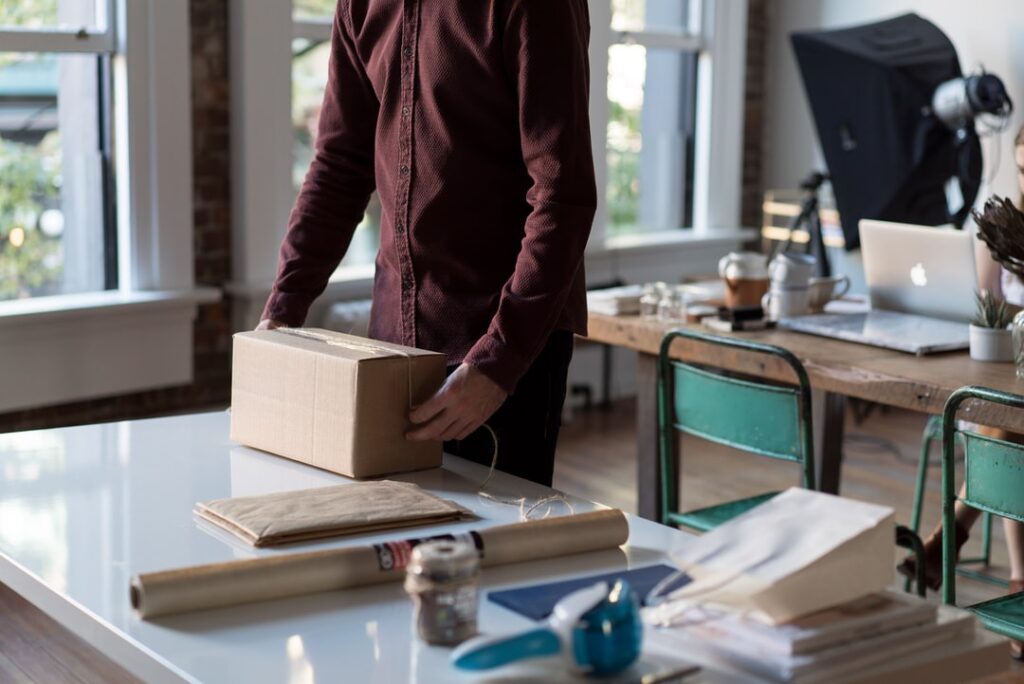 A person sealing a cardboard box on a table.