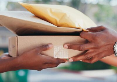 The hands of two people shown as one passes a small stack of packages to the other.