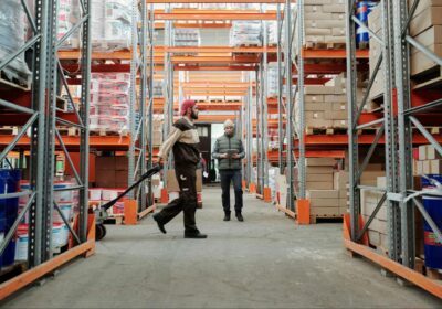 Two people in between large aisles in a warehousing and fulfillment center.